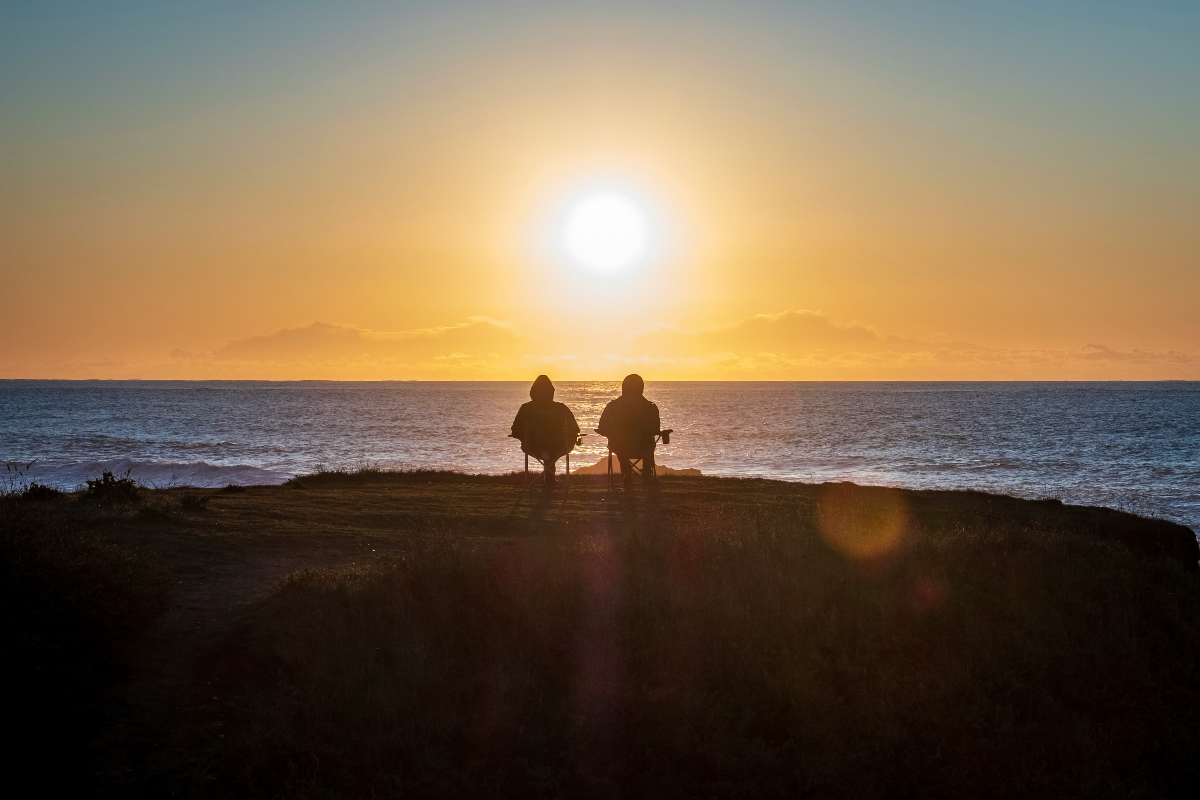 Two people watching the horizon at sunset